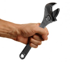 Hand gripping an adjustable wrench, symbolizing plumbing repair and maintenance services related to common plumbing emergencies.