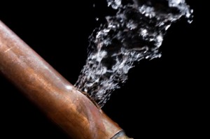 Bursting copper pipe spraying water, illustrating a plumbing emergency situation relevant to urgent plumbing service advice.