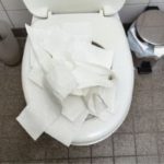 Toilet with excessive toilet paper, highlighting common cause of clogs and maintenance issues related to bathroom plumbing.