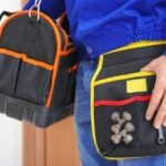 Plumber holding tool bags, showcasing essential equipment for industrial plumbing services.