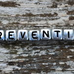 Preventive maintenance spelled out in letter beads on a rustic wooden surface, emphasizing the importance of plumbing upkeep to avoid issues like low water pressure.