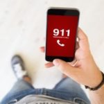 Person holding smartphone displaying emergency call screen for 911, emphasizing the importance of immediate assistance during gas leaks.