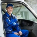 Plumber in blue uniform sitting in service vehicle, ready for gas leak detection and repair services.