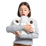 Woman surprised while holding multiple rolls of toilet paper, emphasizing the importance of toilet maintenance and preparedness for plumbing issues.