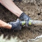 Plumber repairing a pipe in the ground, demonstrating essential plumbing maintenance services offered by The Plumbing Dr in Falls Church, VA.