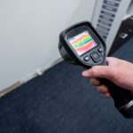 Hand holding a thermal imaging camera detecting moisture in a wall, illustrating leak detection services by The Plumbing Dr.