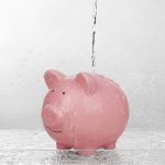 Piggy bank with water leaking from above, symbolizing financial loss due to plumbing issues like slab leaks.