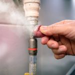 Hand adjusting a gas line connection with visible gas leak, emphasizing the importance of gas leak detection and repair services.