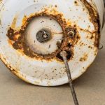 Rusty water heater tank with visible corrosion and deteriorating metal, indicating potential inefficiency and need for replacement or repair.