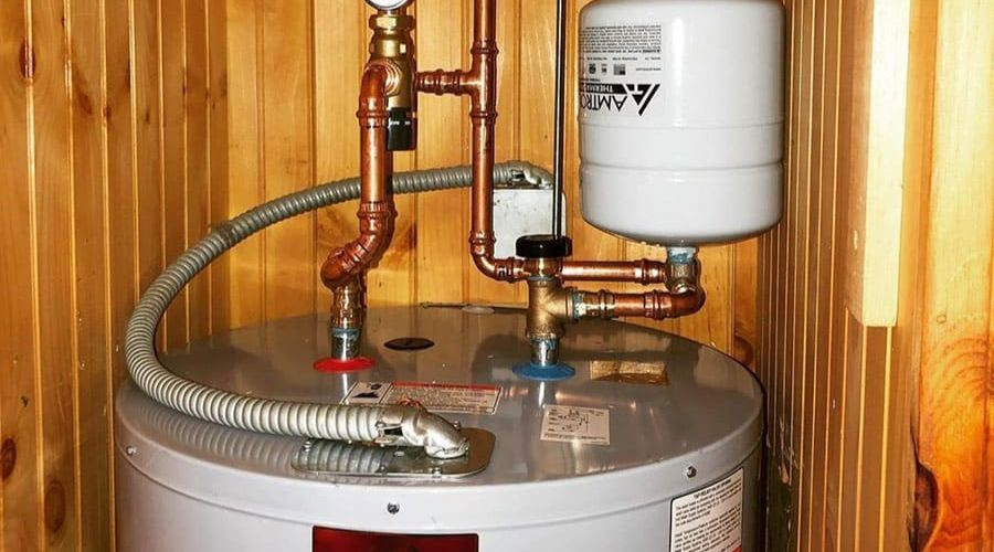 Water heater with copper and flexible piping, located in a wooden enclosure, illustrating essential plumbing maintenance for homeowners.