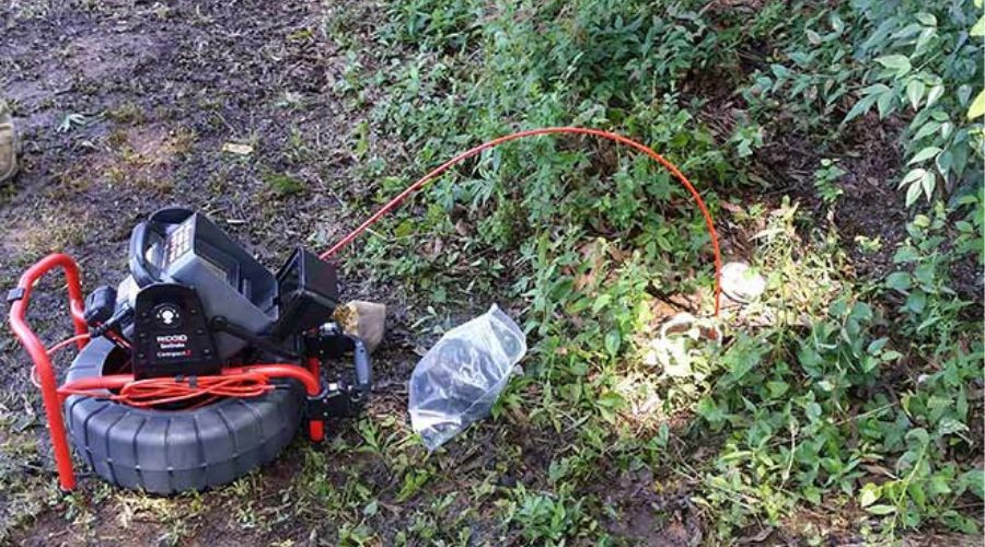 Sewer inspection equipment with a camera and cable in a grassy area, highlighting plumbing maintenance tools for homeowners.